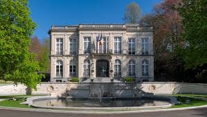 Plombier Auderghem devant l'Hôtel communal art déco, rue paisible avec arbres et maisons bruxelloises typiques en brique.