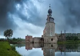 Plombier Colfontaine devant une maison typique en briques rouges avec jardin, rue calme bordée d'arbres et enseignes locales
