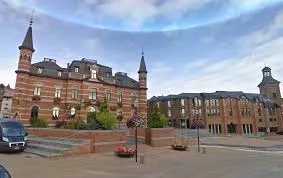 Plombier Frameries rue animée avec maisons en briques typiques et commerces locaux, reflet de l'architecture et de la vie locale