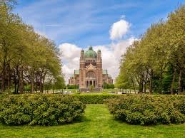 Plombier Ganshoren camion jaune devant une maison de briques rouges typique de la commune, rue calme avec arbres et trottoirs.