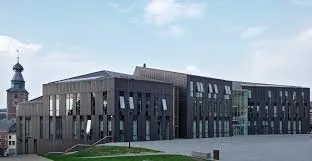 Plombier Gembloux devant l'hôtel de ville historique en pierre, scène typique du centre urbain avec architecture locale.