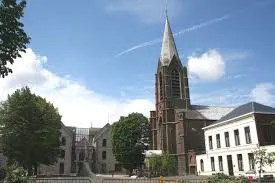 Scène urbaine gestionnaire avec un plombier vérifiant les tuyaux d'un bâtiment ancien typique de Manage en Belgique.