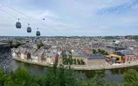 Vue sur une rue animée de Namur avec enseigne de plombier local, bâtiments traditionnels et passants en journée.