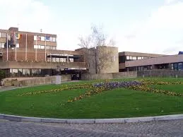 Plombier Sambreville van stationné devant l'hôtel de ville moderne, bâtiment en briques rouges typique du centre urbain.